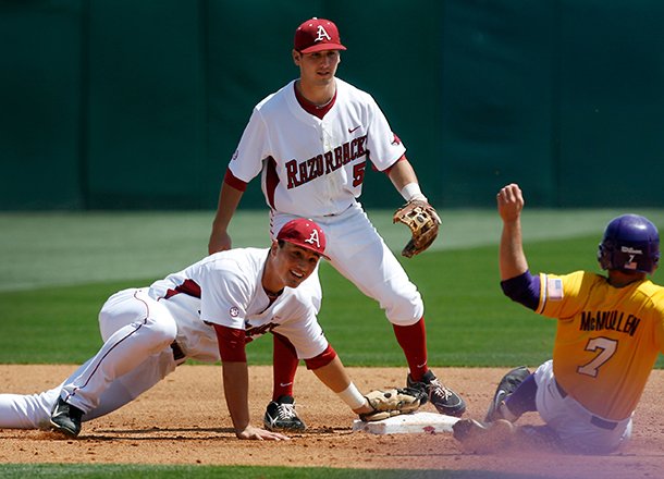 Arkansas shortstop Brett McAfee (center) watches as second baseman Jordan Farris dives to make a force out at second on LSU's Sean McMullen in the top of the third inning on Sunday, April 14, 2013, at Baum Stadium in Fayetteville.