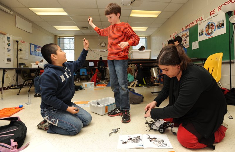 Bob Li, 9, left, and John Michael McCarthy, 9, get some help Wednesday from club facilitator Bayleigh Jones of
Springdale during a meeting of the Robotics Club at Leverett Elementary School in Fayetteville.