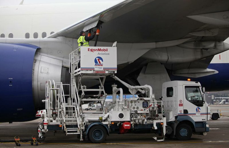 An employee connects a fuel hose from an Exxon Mobil Corp. aviation fuel pumping truck to a British Airways jet at Gatwick airport near London in January. Exxon on Thursday reported a first quarter profit of $9.5 billion. 