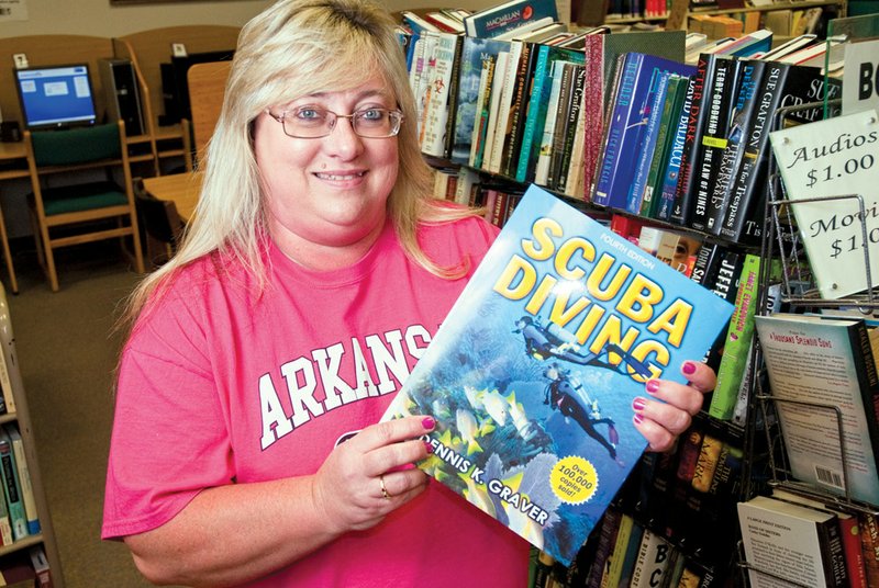 Daniece Howard, interim librarian at the Arlene Cherry Memorial Library in Cabot, holds a book on one of the subjects to be presented during the summer reading program.