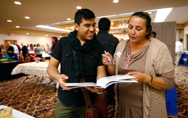 Fernando Gallardo, left, a Fayetteville High School senior, talks Friday to Loree Alrawhani with the Arkansas Workforce Center during a job expo at the GuestHouse International Hotel in Fayetteville. Students visited with about 30 businesses and colleges during the event. 