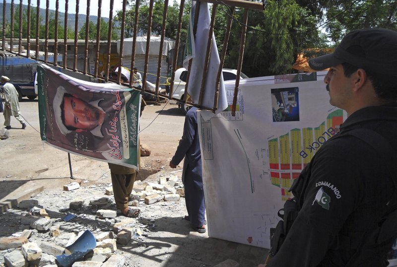 A Pakistani police officer stands guard near an office of a local politician following a blast in Kohat, Pakistan on Sunday, April 28, 2013. Pakistani Taliban detonated bombs at the campaign offices of two politicians in the country’s northwest on Sunday, police said, killing many people in an escalation of attacks on secular, left-leaning political parties. 