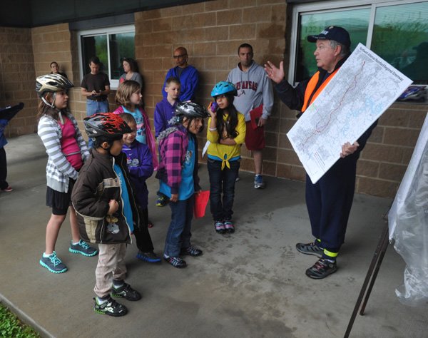 Dave Bowman, Trail Trekker volunteer coordinator with Fayetteville’s Parks and Recreation Department, talks Saturday to kids about bike trail safety Saturday morning before the start of the Family Bike Ride for students and families at Owl Creek School . 