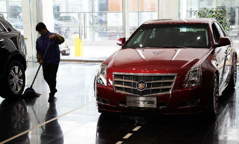 A worker cleans near a General Motors Co. Cadillac CTS vehicle displayed at a dealership in Shanghai, China, on Friday, Feb. 8, 2013. China's services industries grew at the fastest pace since August as gains in retailing and construction aid government efforts to drive a recovery in the world's second-biggest economy. Photographer: Tomohiro Ohsumi/Bloomberg