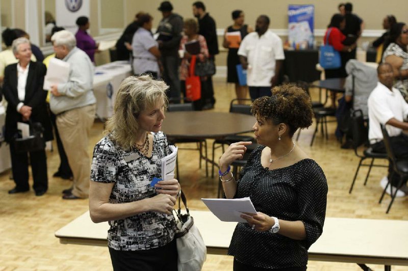 Donna Van Natten (left), with the Enterprise Center, and Valoria Armstrong, with Tennessee American Water Co., talk Tuesday during a job fair in Chattanooga, Tenn. Weekly applications for unemployment benefits fell 18,000 last week, the Labor Department said. 