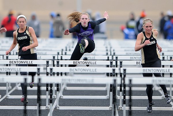 McKenzie Dixon, left, and Logan Morton, right, both of Bentonville flank McKenzie Penne of Fayetteville during the 110-meter preliminary hurdles race Thursday at Tiger Athletic Complex in Bentonville during the Class 7A State Track and Field Championships. 
