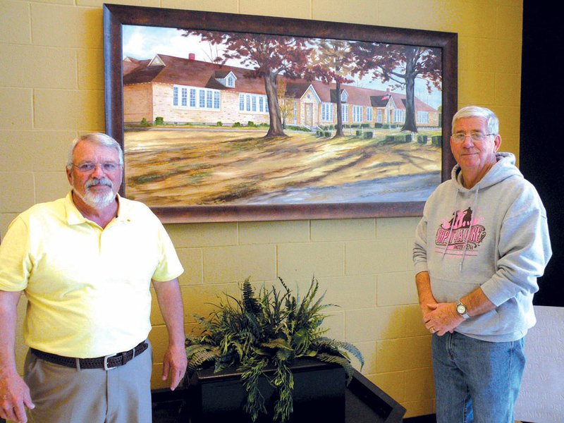 Don Rowlett, left, and Lynn Burford are members of the Quitman School Alumni Association Inc., which will sponsor the annual alumni reunion May 25 at Quitman High School. They are shown here in the foyer of the new Quitman High School, which was completed in 2010. On the wall behind them is a painting by Gary Reeves of the former school building, known as Old Main. Reeves also painted a bulldog, the school’s mascot, in the entryway.