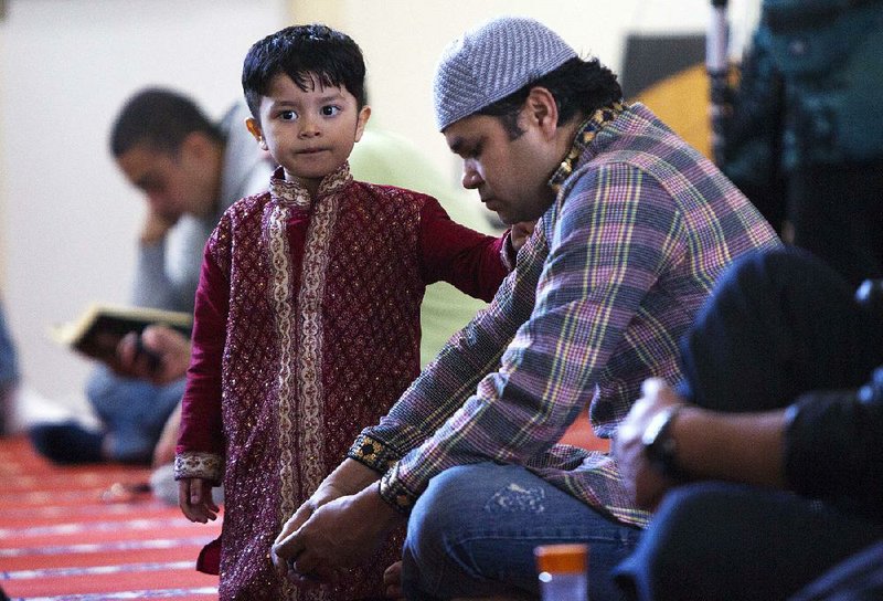 A boy stands next to his father during a prayer service at the Islamic Society of Boston mosque in Cambridge, Mass. American Muslims feared backlash from the Boston bombings after the suspects were identified as Muslims but few have reported acts of retaliation. 