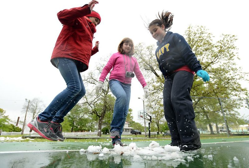 Fayetteville middle school students Abby Stocker (from left), Emily Ware and Kalley Sutherland stamp snowballs Friday during a field-trip stop at Kindley Park in Gravette. 