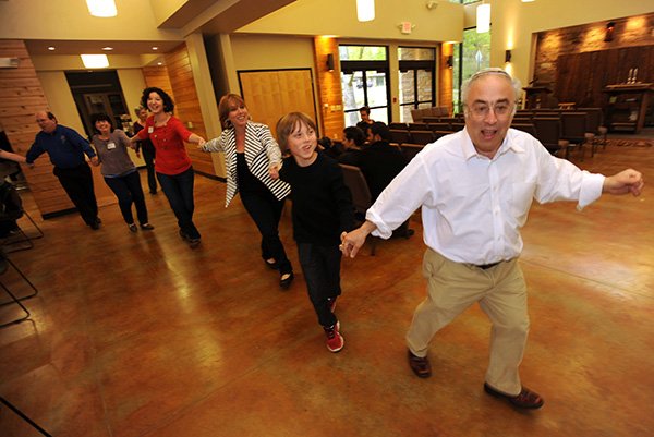 Rabbi Jacob Adler, right, leads a group of worshipers through the temple April 26, while demonstrating a dance that is part of a traditional Jewish service at the Temple Shalom in Fayetteville. 