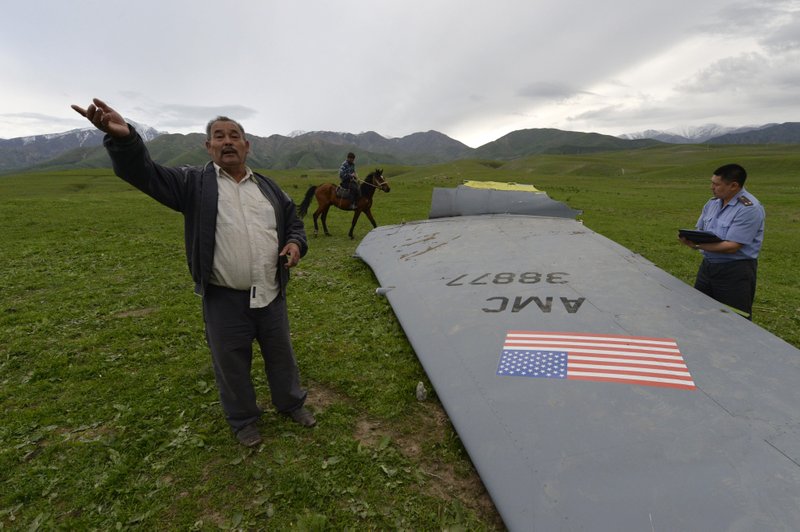 A Kyrgyz policeman investigates a U.S. Air Force KC-135 tanker aircraft wreckage as a local citizen speaks to The Associated Press photographer on a field near the village of Chaldovar, about 100 miles west of the Kyrgyz capital Bishkek, Friday, May 3, 2013. The emergencies ministry in Kyrgyzstan says a US military plane has crashed in the country. Kyrgyzstan hosts a US base that is used for troops transiting into and out of Afghanistan and for C-135 tanker planes that refuel warplanes in flight.