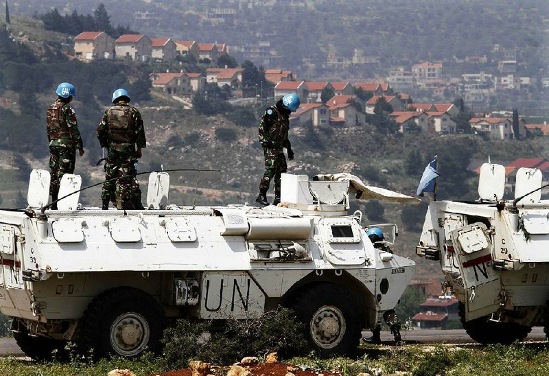 U.N peacekeepers, stand on their armored personnel carrier across the border from the Israeli settlement of Metulla, background, during a patrol at the Lebanese-Israeli border, in the southern village of Kfar Kila, Lebanon, Monday, May 6, 2013. Israel's weekend airstrike on a military complex near the Syrian capital of Damascus killed dozens of Syrian soldiers, a group of anti-regime activists said Monday, citing information from military hospitals. Israeli officials have indicated they will keep trying to block what they see as an effort by Iran to send sophisticated weapons to Lebanon's Hezbollah militia ahead of a possible collapse of Syrian President Bashar Assad's regime. (AP Photo/Mohammed Zaatari)