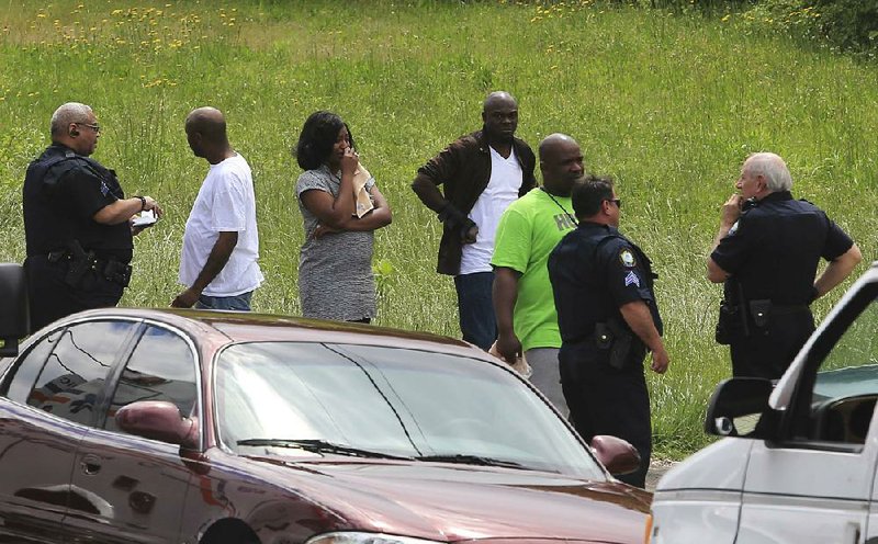 Little Rock Police officers question some of the people that gathered outside the scene of a double homicide in a home at 1513 West 33rd St. in Little Rock Monday. A man and a woman were found dead in the home.