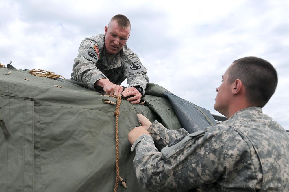 STAFF PHOTO ANTHONY REYES
Sgt. 1st Class  Morgan Whorton, left, and Spc. Joshua Wilson, both with Bravo Battery 2-142 Field Artillery of the Arkansas Army National Guard stationed in Siloam Springs, assemble a frame tent Wednesday, May 8, 2013 at J.B. Hunt Park in Springdale. The tent will be used as a hospitality tent for coaches and officials attending the 7A State Softball Tournament starting Thursday.