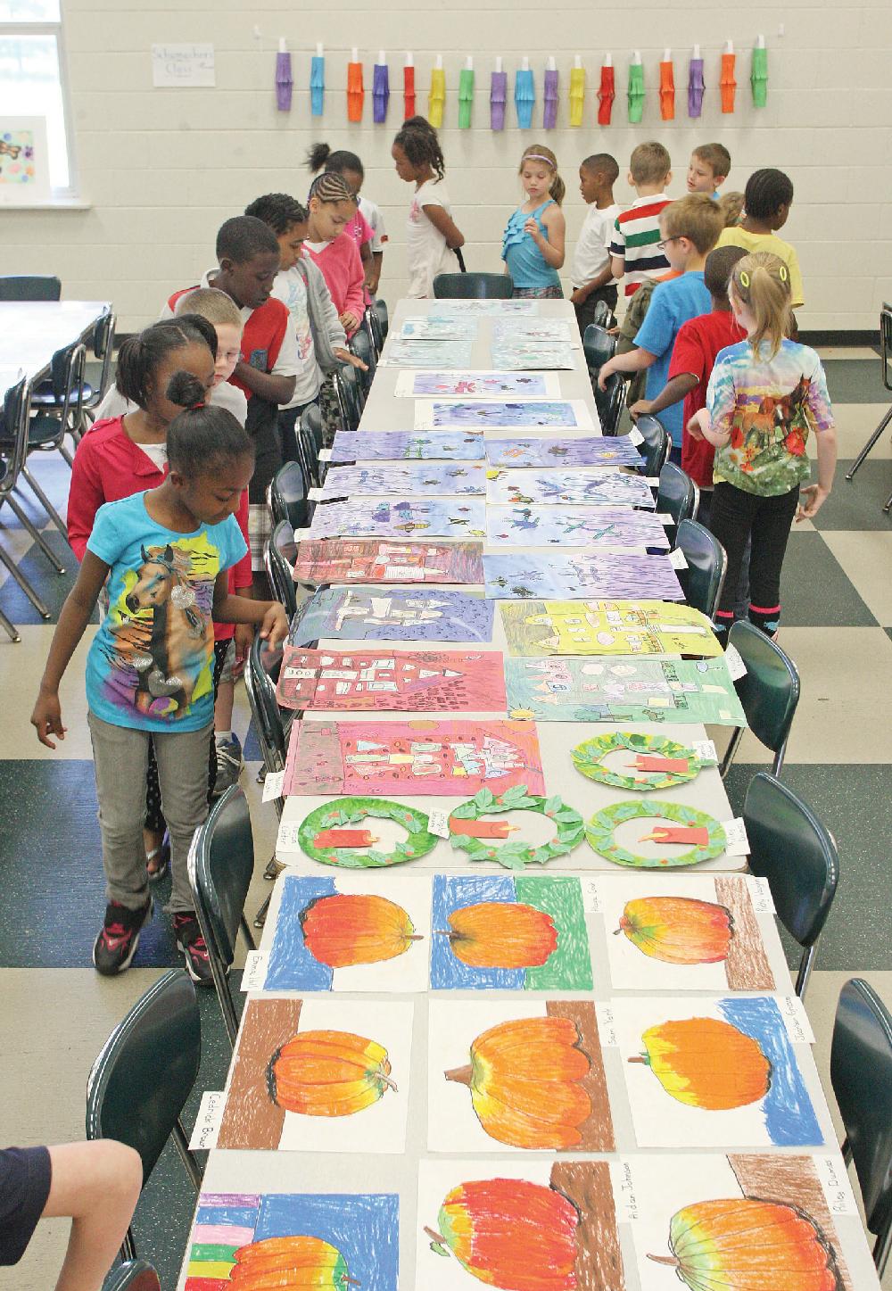 El Dorado News-Times/Michael OrrellArt on display: Yocum Elementary students admire the art work of fellow classmates during the school’s annual Art Show in the school cafeteria on Wednesday. The works are from Janice Roscoe’s kindergartner through fourth-grade art students from throughout this school year that includes different art mediums such as water coloring, chalk, pen, crayon and clay.