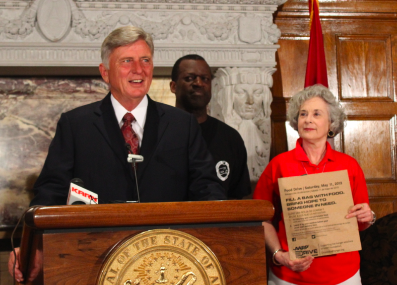 Gov. Mike Beebe speaks about the Stamp Out Hunger food drive Thursday while a supporter holds one of the paper bags that will be used to collect food items from homes across the state.