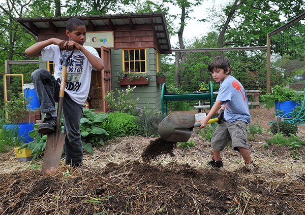 Tyrec Nance, 11, left, and Laine Adams, 6, both from Fayetteville, work Thursday on digging holes for tomato plants at the community garden next to the Yvonne Richardson Community Center in Fayetteville. The garden program is just one of the many after school program offered at the center. 
