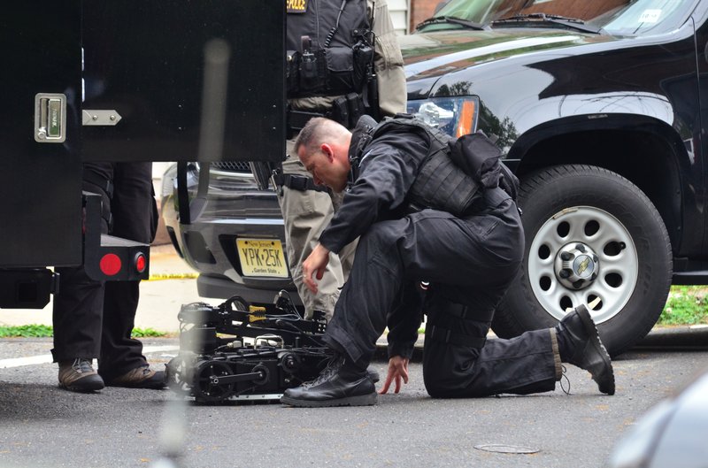 A state police swat team member readies a robot to enter a home where a man had barricaded himself on Friday, May 10, 2013 in Trenton, N.J. The standoff with an armed man who police said took multiple hostages entered its second day Saturday as authorities worked to negotiate his surrender and his captives' safe release. The man, whose identity has not been released, was holed up in a brick house in South Trenton more than 18 hours after the standoff began Friday afternoon, authorities said. 