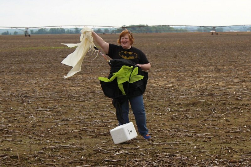 Wendy Kittler, Gifted and Talented Program Coordinator at England School District, stands with the popped weather balloon, parachute and package that 22 of her students helped launch to the edge of the earth Thursday, May 9. Educators Andy Beck and Michael Love helped Kittler coordinate the project.