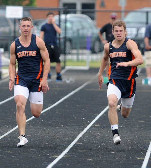 Alex Miles, left, and Daniel Spickes, both of Rogers Heritage, race side-by-side Wednesday during the 100-meter dash at Ramay Junior High in Fayetteville during Day 1 of the decathlon and heptathlon state meets. 