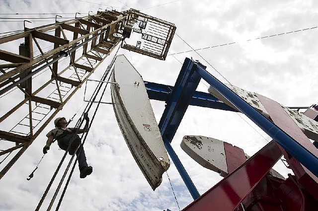 FILE - In this Tuesday, July 26, 2011 file photo, Ben Shaw hangs from an oil derrick outside of Williston, N.D. The surge in oil production in the U.S. and Canada and shrinking oil consumption in the developed world is transforming the global oil market.  (AP Photo/Gregory Bull, File)