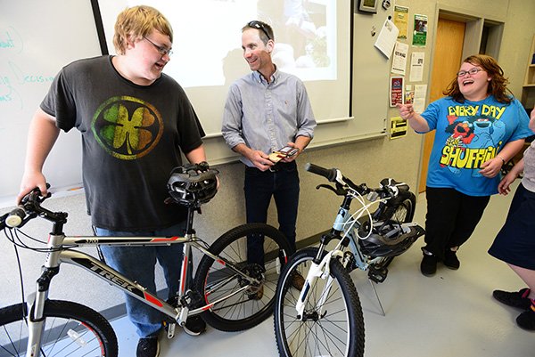 Bryon Moudy, center, master fit technician for Phat Tire Bike Shop, presents Coulter Fitzner, 17, and Breanna Swadley, 16, with new Trek mountain bikes Friday, May 17, 2013, during their small business operations class at Bentonville High School. The students were awarded the bicycles by Moudy for their class attendance history and completing a 3-part essay.