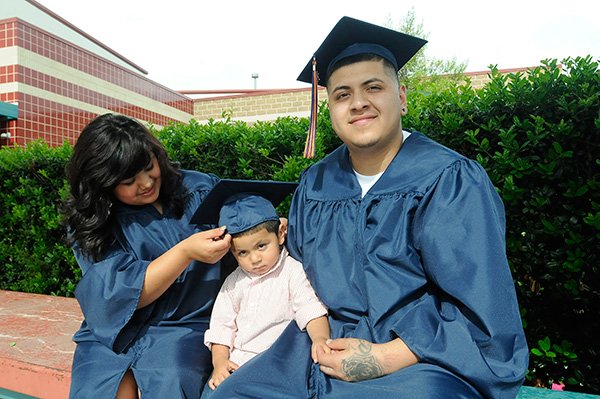 Percela Velasco lets her son, Manuel, age 2, try on her graduation cap on Thursday May 16 2013. She and her husband, Manny Hernandez, right, graduated from Rogers Heritage High School on Friday.