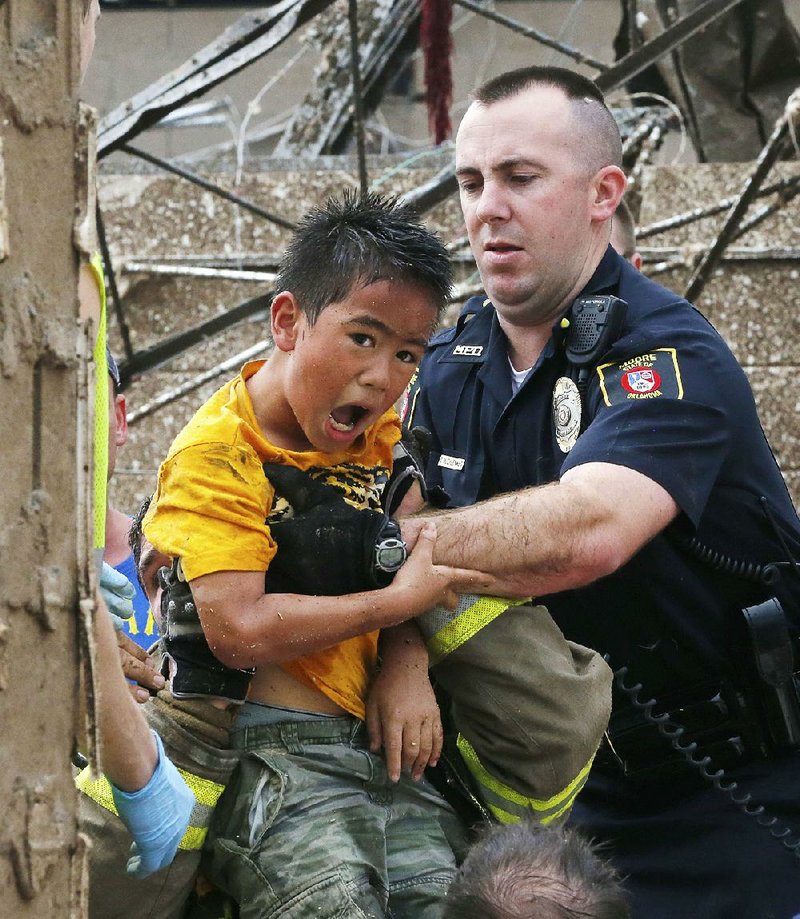 A boy is pulled from beneath a collapsed wall at the Plaza Towers Elementary School following a tornado in Moore, Okla., Monday, May 20, 2013. A tornado as much as a mile (1.6 kilometer) wide with winds up to 200 mph (320 kph) roared through the Oklahoma City suburbs Monday, flattening entire neighborhoods, setting buildings on fire and landing a direct blow on the elementary school. (AP Photo Sue Ogrocki)