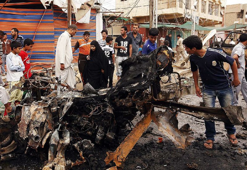 Civilians inspect the scene of a car bomb attack in the Kamaliyah neighborhood, a predominantly Shiite area of eastern Baghdad, Iraq, Monday, May 20, 2013. A wave of car bombings across Baghdad’s Shiite neighborhoods and in the southern city of Basra killed and wounded scores of people, police said. (AP Photo/ Hadi Mizban)