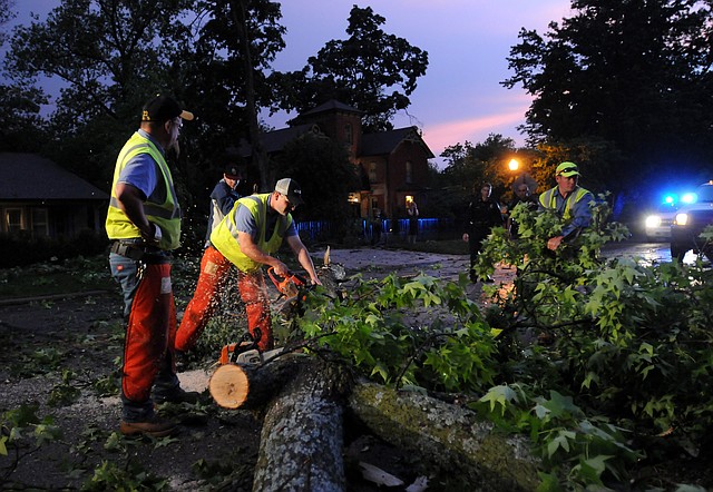 Workers from the Bentonville Street Department use chainsaws to cut down and clear a tree which broke off and fell into East Central Avenue at 305 E. Central Ave. in Bentonville. 