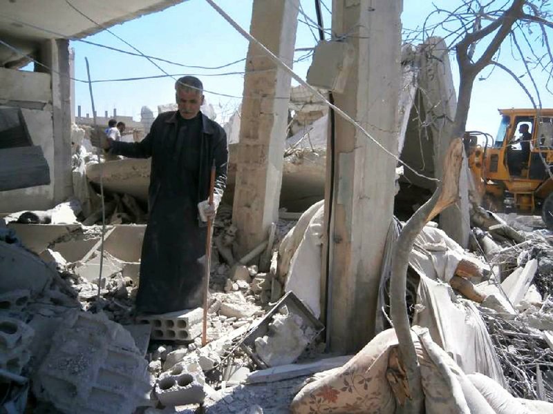 This citizen journalism image provided by Qusair Lens, which has been authenticated based on its contents and other AP reporting, shows a Syrian man checking his destroyed house that was damaged by a Syrian forces air strike in the town of Qusair, near the Lebanon border, Homs province, Syria, Tuesday, May 21, 2013. Several members of Lebanon's militant Hezbollah group died of wounds sustained while fighting for control of a strategic Syrian town near the Lebanese border, activists said Tuesday, as the battle in the area raged for its third straight day. (AP Photo/Qusair Lens)