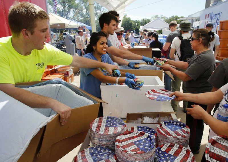Jeff Sherwood (from left), Saba Naseem and Logan Webster, all of Fayetteville, help serve lunch to about 4,000 people Wednesday at a church in Moore, Okla. 