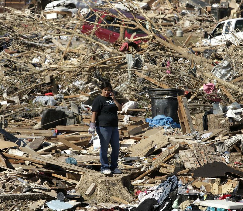 A woman stands on a stump in a sea of rubble Wednesday as people sort through the wreckage of their homes in a neighborhood of Moore, Okla. 