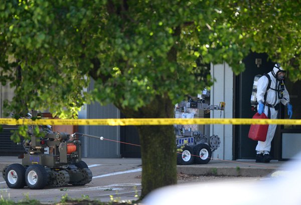 A member of the Bentonville Police Bomb Squad removes a gasoline can Wednesday from a room at a vacant hotel on Southeast Walton Boulevard near U.S. 71 in Bentonville. A police officer patroling the vacant hotel just before 7 a.m. discovered suspicious items, including a 5-gallon chlorine bucket, PVC pipes and wiring, inside a room after noticing an open door. 