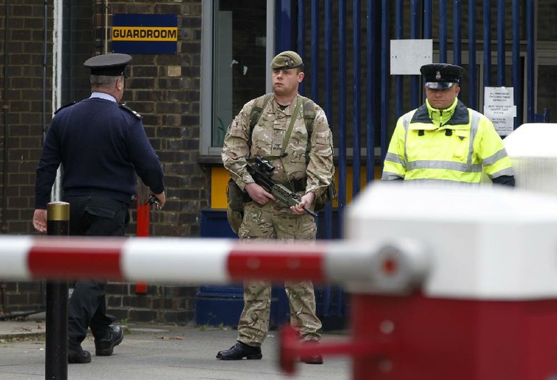 A soldier stands guard Thursday at the gate of the Royal Artillery Barracks near the scene of a terror attack in Woolwich, southeast London. Police remained at the scene throughout the night after an attack Wednesday, which left one member of the armed forces dead and two suspects injured and hospitalized.