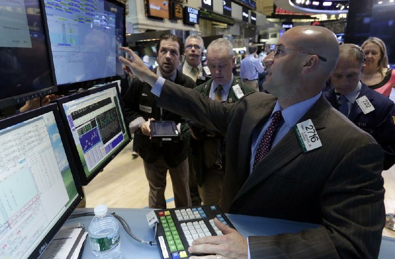 Specialist Henry Becker works with traders Thursday at his post on the floor of the New York Stock Exchange. 