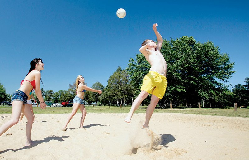 Kayla Hughes, center, gets in position to hit the ball that Mac Harris, right, was unable to connect with during a beach volleyball game at Sandy Beach in Heber Springs. At the left is Ashley Bremer.