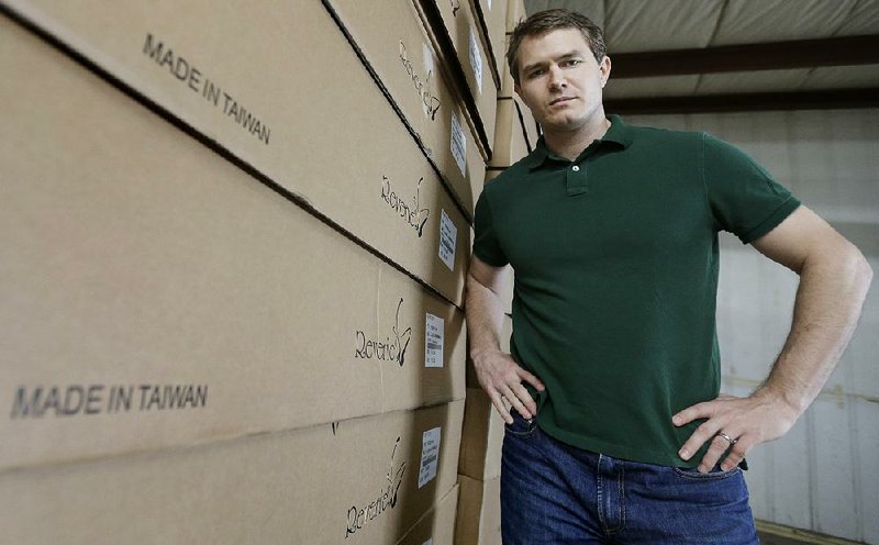 In this Friday, May 17, 2013, photo, Martin Rawls-Meehan, CEO of Reverie, poses at the company warehouse, next to product made in Taiwan. The company is working to expand manufacturing in the United States. (AP Photo/David Duprey)