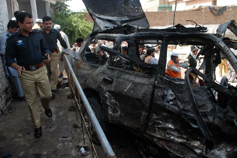 Pakistani police officers visit the site of an explosion in Peshawar on Friday. Police say a suicide bomber walked up to a vehicle owned by an Afghan religious leader in northwestern Pakistan and set off explosives, killing several people. The leader, Haji Hayatullah, was not harmed in the attack because he was in a nearby mosque attending Friday prayers. 
