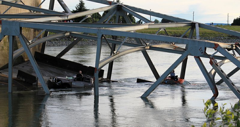 In this photo provided by Francisco Rodriguez, one man is seen sitting atop a car that fell into the Skagit River another stands in the door of his partially submerged pickup truck after the collapse of the Interstate 5 bridge there minutes earlier Thursday, May 23, 2013, in Mount Vernon, Wash. 