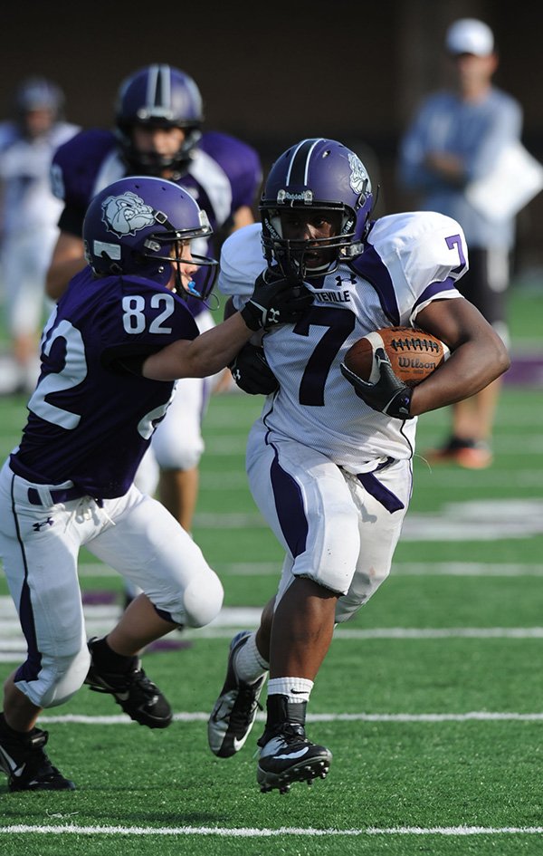 Fayetteville’s Rashad Brown, right, fends off Andrew Moore as he carries the ball through the defense during the annual spring Purple-White game Friday at Harmon Stadium. 