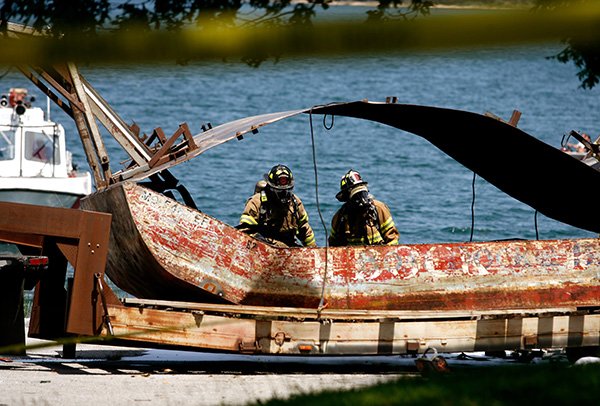 Northeast Benton County firefighters survey the damage Friday to a barge following explosions near the boat ramp at the Lost Bridge North Park in Garfield. One person died from the explosion believed to be caused from an oxygen tank. 