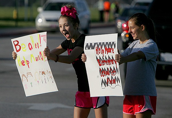 Olivia Lisle, left, and Caroline Rhodes, both Hellstern Middle School seventh-graders, promote donations Friday for tornado victims in Moore, Okla., in front of the school as students are dropped off at the Springdale school. 