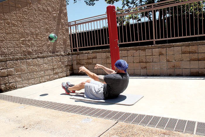 David Chappell uses a wall on the pool deck at Little Rock Racquet Club to do the Sit-up Toss, using a weighted ball with enough bounce that it returns to him. 