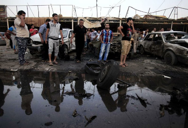 Iraqis gather at the scene of a car bomb attack at a used cars dealers parking lot in Habibiya neighborhood of eastern Baghdad, Iraq, Monday, May 27, 2013. A wave of car bombings tore through mostly Shiite Muslim neighborhoods of the Baghdad area, killing and wounding dozens of people, police said, in the latest outburst of an unusually intense wave of bloodshed roiling Iraq. The blasts are the latest indication that Iraq's security is rapidly deteriorating. (AP Photo/Karim Kadim)
