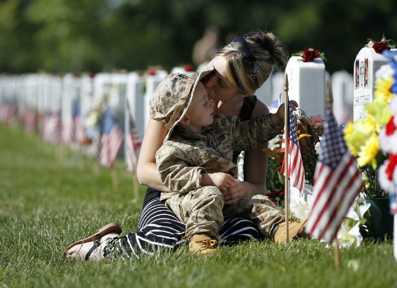Brittany Jacobs kisses her son Chris near the grave site of her late husband, Christopher Jacobs, at Section 60 on Memorial Day at Arlington National Cemetery in Arlington, Virginia, Monday, May 27, 2013. Iraq and Afghanistan war veterans are buried in Section 60. (AP Photo/Molly Riley)  