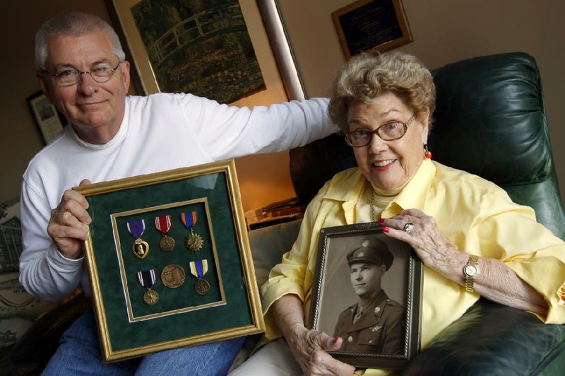 Joe Cowan and his mother, Cloteen Cowan, show a photo of Frank Kirby Cowan when he was drafted in 1942 and the war medals he received after being released from a year-long imprisonment in several German concentration camps during World War II. 