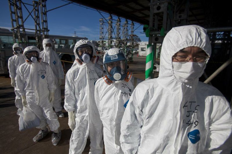 Workers in protective suits and masks wait to enter the emergency operation center at the crippled Fukushima Dai-ichi nuclear power station in November 2011 in Okuma, Japan. 