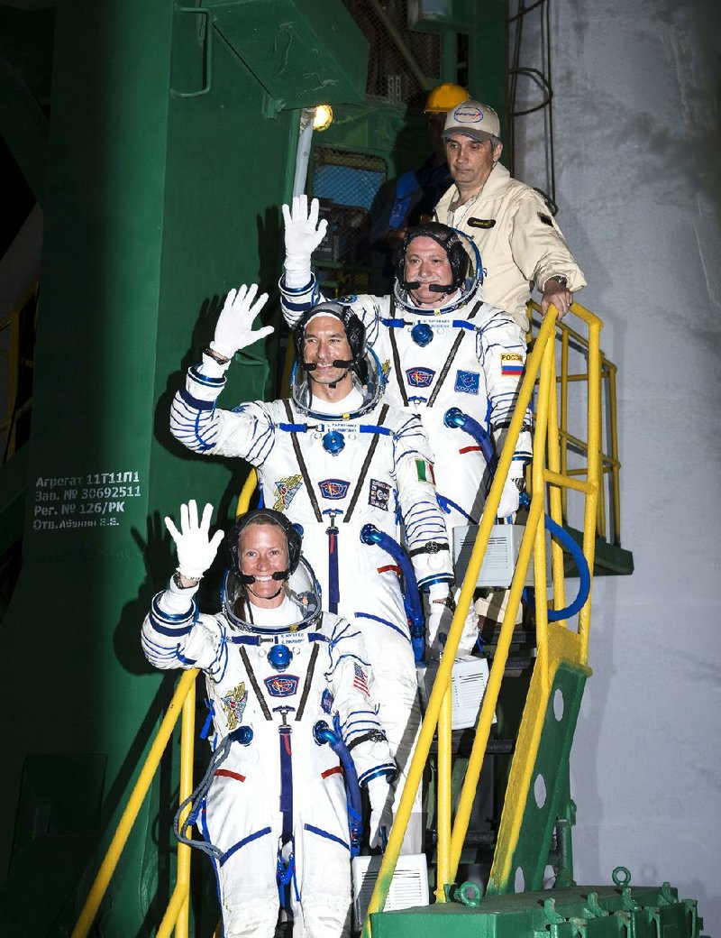 In a photo provided by NASA Expedition 36/37 Soyuz Commander Fyodor Yurchikhin of the Russian Federal Space Agency, top, Flight Engineers Luca Parmitano of the European Space Agency, center, and Karen Nyberg of NASA,  wave as they board the Soyuz rocket ahead of their launch to the International Space Station, early Wednesday, May 29, 2013,  in Baikonur, Kazakhstan.  Yurchikhin, Nyberg, and, Parmitano, will remain aboard the station until mid-November. (AP Photo/NASA, Bill Ingalls)