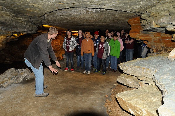 Donald Locander shows students from St. Raphael Catholic School in Springdale how they would have needed to crawl to see this portion of the cave before it was opened up during an expansion project. Workers used dynamite to open a 94-foot tunnel to a part of the cave that contains formations and a lagoon. 